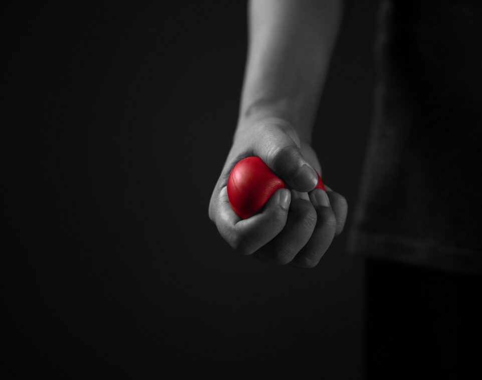 Mano apretando pelota roja - Línea de ayuda